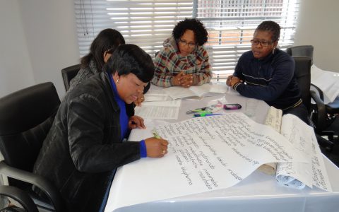 Teachers preparing flip charts in Sesotho to use when presenting WWP to parents